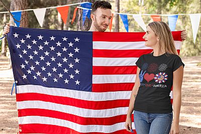 Peace Love America Sunflower 4th of July America Flag Hippie T-Shirt - Happy Patriotic 4th July Day-t-shirt-mockup-of-a-blond-woman-standing-next-to-an-american-flag